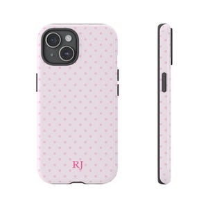 May include: A light pink phone case with a repeating pattern of small, evenly spaced pink polka dots. The case has a black camera housing and black side buttons. The initials "RJ" are printed in pink at the bottom.