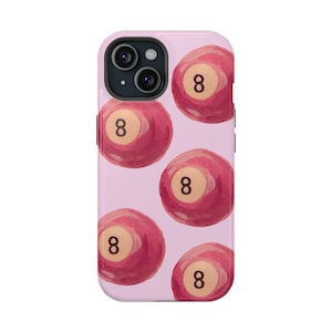 Pode incluir: Uma capa de telefone rosa com um padrão de bolas de bilhar vermelhas com o número 8. A capa tem um recorte para a lente da câmera.