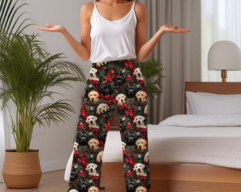 May include: Black, white, and yellow Labrador Retriever puppy print pajama pants. The pants feature a festive holiday design with red poinsettias and green foliage. The pajama pants have a comfortable, relaxed fit.