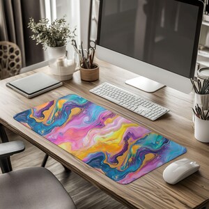 May include: A colorful abstract marble design mousepad with blue, purple, pink, yellow, and gold swirls. The mousepad is on a wooden desk with a computer, keyboard, and mouse.