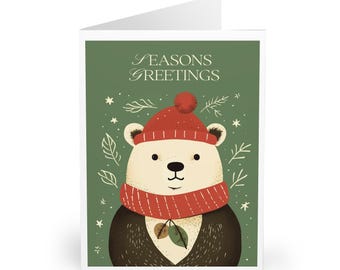 Puede incluir: Una tarjeta de felicitación plegada con un oso de dibujos animados que lleva un gorro y una bufanda rojos. El oso está sobre un fondo verde con las palabras "SEASONS GREETINGS" en la parte superior. El oso tiene una cara color crema y una nariz y ojos negros.