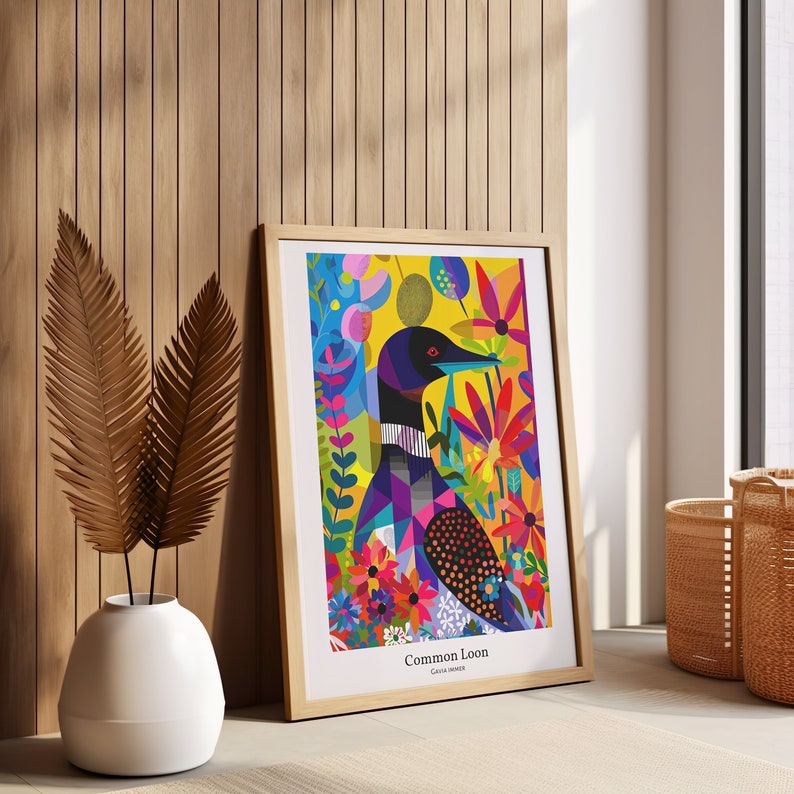 Pode incluir: Uma impress&atilde;o art&iacute;stica emoldurada com uma ilustra&ccedil;&atilde;o colorida de um Common Loon. A obra de arte mostra o p&aacute;ssaro em meio a flores e folhagens vibrantes, com um fundo amarelo. A impress&atilde;o est&aacute; em uma moldura de madeira clara.