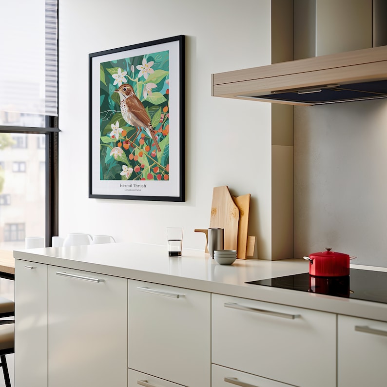May include: A framed art print featuring a Hermit Thrush bird illustration. The artwork showcases the bird perched on a branch with berries and white flowers against a green background. The print is displayed in a modern kitchen setting.