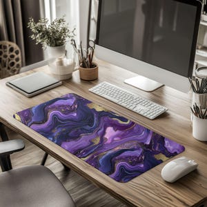 May include: A rectangular mouse pad with a swirling design in shades of purple, blue, and gold. The desk accessory is on a wooden desk with a computer, keyboard, and mouse.