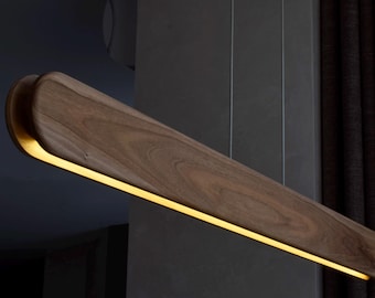 May include: A long, rectangular wooden light fixture with a warm, yellow light emanating from a thin strip of LED lights running along the center of the fixture.
