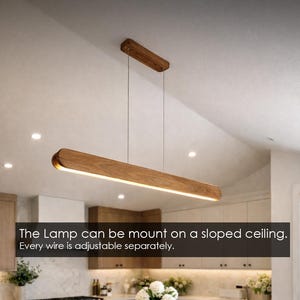 Peut inclure: Luminaire suspendu rectangulaire en bois avec source de lumière linéaire. Le luminaire est suspendu au plafond par des fils fins. Le texte dit: La lampe peut être montée sur un plafond incliné. Chaque fil est réglable séparément.