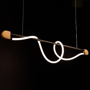 May include: A modern pendant light fitting with a black metal rod and a white LED light that is shaped like a loop. The light is suspended from the ceiling by two cords and has wooden end caps.