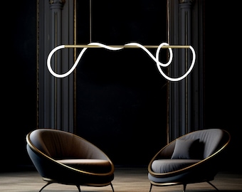 May include: Modern, minimalist pendant light fixture with a gold-toned horizontal bar and a looping, white neon light design. The light hangs above two dark gray, rounded armchairs with gold trim, set against a dark background.