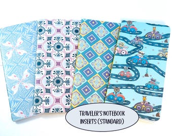 May include: Four rectangular traveler's notebook inserts with distinct patterns: light blue floral, pink and dark blue geometric, yellow and blue diamond tile, and a light blue background with cartoon animals driving colorful cars.