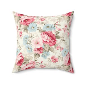 May include: A cream-colored pillow with a floral pattern featuring pink, red, and blue flowers. The pillow is made of a soft, comfortable fabric and is perfect for adding a touch of elegance to any room.