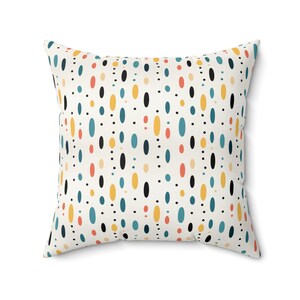 May include: A white throw pillow with a geometric pattern of black, yellow, orange, and blue circles and ovals.