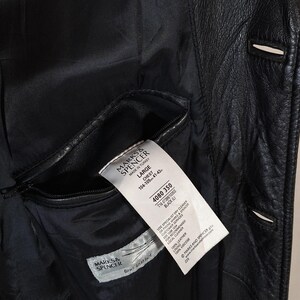 May include: Black leather jacket with a visible interior pocket and a tag from Marks & Spencer. The jacket has a classic design with visible stitching and button details. The tag indicates the jacket is a size Large.