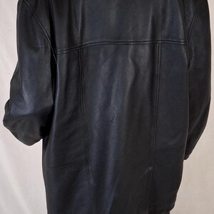 May include: Black leather jacket with a collared neckline and a tailored fit. The jacket features a classic design with a smooth, matte finish. The back of the jacket has a horizontal seam across the upper back and vertical seams.