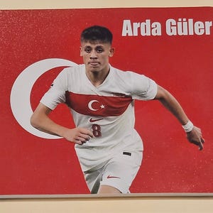 May include: A rectangular mouse pad featuring a red background with a white crescent and star. The image displays a soccer player in a white jersey with the number 8 and the Turkish flag emblem. The text Arda Güler is printed in white.