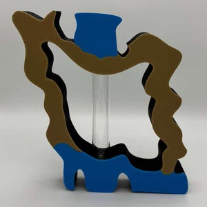 May include: A decorative vase with a unique, abstract design. The vase features a brown, black, and blue color scheme. A clear glass tube runs through the center of the vase. The vase has a modern, artistic aesthetic.