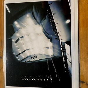 May include: A black and white photograph of a stage with spotlights shining down from the ceiling. The stage is empty and the lights are bright.