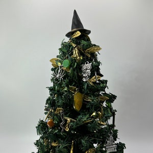 May include: A small artificial Christmas tree decorated with a witch's hat, an owl, a spider, and other Halloween-themed ornaments.