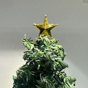 May include: A small, green, paper Christmas tree with a gold star on top.