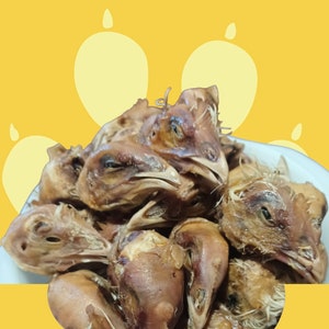 K&ouml;nnte beinhalten: Nahaufnahme eines Stapels H&uuml;hnerk&ouml;pfe, einige mit noch intaktem Schnabel, andere mit entfernten Schnabel. Die H&uuml;hnerk&ouml;pfe sind braun und scheinen gekocht zu sein.