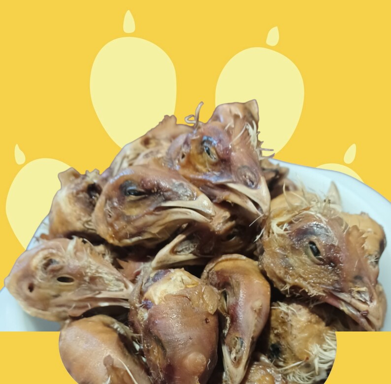 K&ouml;nnte beinhalten: Nahaufnahme eines Stapels H&uuml;hnerk&ouml;pfe, einige mit noch intaktem Schnabel, andere mit entfernten Schnabel. Die H&uuml;hnerk&ouml;pfe sind braun und scheinen gekocht zu sein.