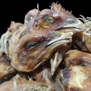 K&ouml;nnte beinhalten: Nahaufnahme eines Stapels getrockneter H&uuml;hnerk&ouml;pfe. Die K&ouml;pfe sind braun und haben eine leicht gummiartige Textur.