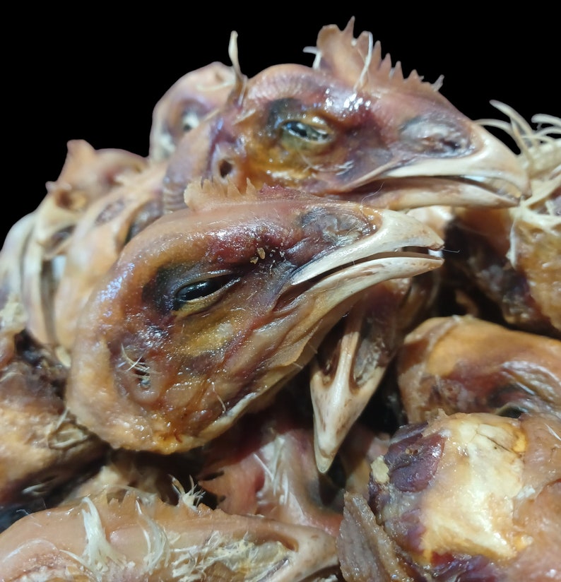 K&ouml;nnte beinhalten: Nahaufnahme eines Stapels getrockneter H&uuml;hnerk&ouml;pfe. Die K&ouml;pfe sind braun und haben eine leicht gummiartige Textur.