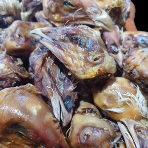 K&ouml;nnte beinhalten: Nahaufnahme eines Stapels getrockneter H&uuml;hnerk&ouml;pfe. Die K&ouml;pfe sind braun und haben eine leicht gummiartige Textur. Sie sind eine beliebte Zutat in einigen asiatischen K&uuml;chen.