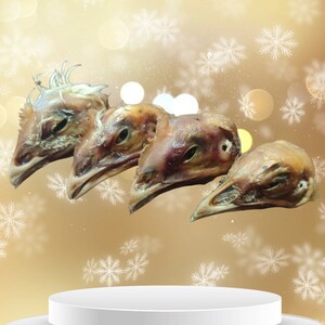 K&ouml;nnte beinhalten: Vier getrocknete H&uuml;hnerk&ouml;pfe auf einem wei&szlig;en Sockel vor einem goldenen Hintergrund mit wei&szlig;en Schneeflocken.