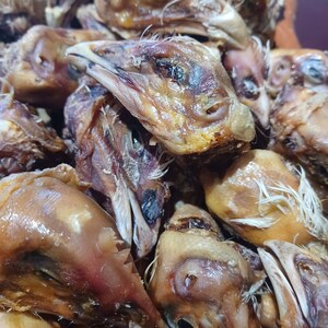 K&ouml;nnte beinhalten: Nahaufnahme eines Stapels getrockneter H&uuml;hnerk&ouml;pfe. Die K&ouml;pfe sind braun und haben eine leicht gummiartige Textur.