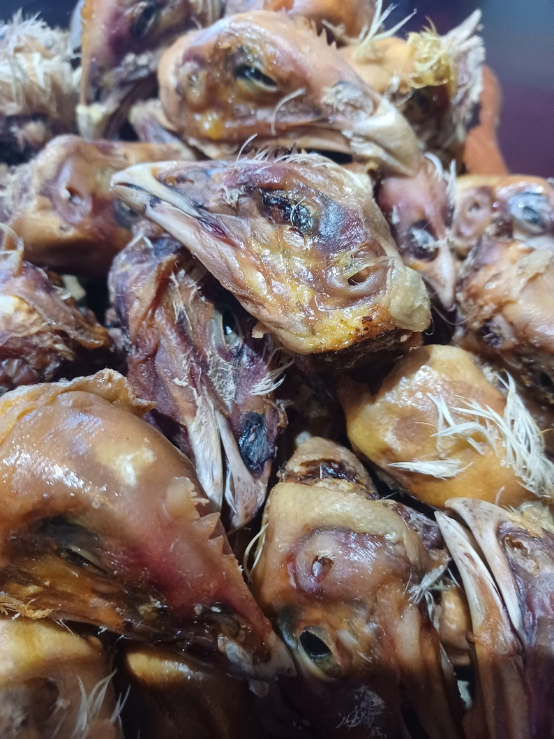 K&ouml;nnte beinhalten: Nahaufnahme eines Stapels getrockneter H&uuml;hnerk&ouml;pfe. Die K&ouml;pfe sind braun und haben eine leicht gummiartige Textur.