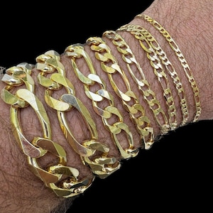 May include: A set of gold chain bracelets of varying widths and lengths. The chains are all made of a classic, flat, oval-shaped link.