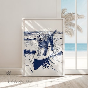 Puede incluir: Un estampado enmarcado con una ilustración azul marino de un perro surfeando. La obra de arte representa al perro en una tabla de surf en medio de olas del océano y una escena de playa. El estampado está en un marco blanco y se exhibe en interiores.