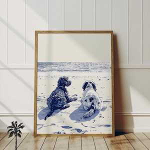 May include: A framed print featuring two dogs on a beach, rendered in shades of blue and white. The artwork depicts a black dog and a white and black dog, both facing away from the viewer. The print is in a wooden frame, with the text "Lucky Day Decor" at the bottom.