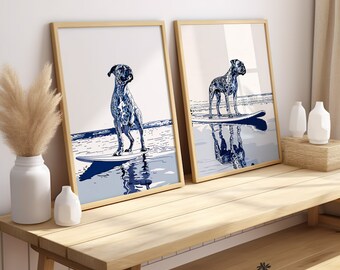 May include: Two framed prints of a blue and white illustration of a dog surfing on a surfboard. The prints are in wooden frames and are hanging on a wall.