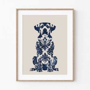 May include: A framed print featuring a sitting dog silhouette filled with a navy blue floral pattern. The dog is set against a beige background, and the artwork is enclosed in a light brown wooden frame.