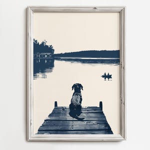 Puede incluir: Impresión enmarcada que muestra un perro sentado en un muelle de madera, contemplando un lago sereno. La obra de arte utiliza tonos azules y crema, con una cabaña y una barca en la distancia. El perro es el foco principal.