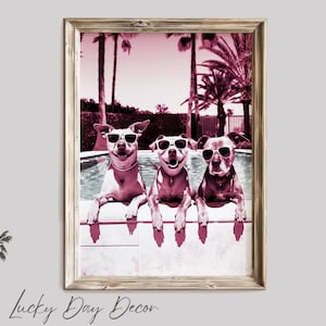 May include: Three dogs wearing sunglasses are sitting on the edge of a swimming pool. The dogs are in a pink and white color scheme. The background is a blurred image of palm trees and a pool.