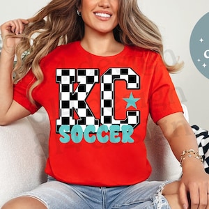 Puede incluir: Camiseta roja con un gráfico "KC" a cuadros en blanco y negro y la palabra "SOCCER" en letras azul turquesa.
