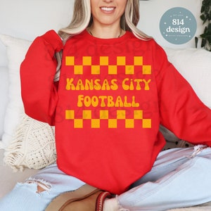 May include: A red sweatshirt with a yellow checkerboard pattern and the words "Kansas City Football" in yellow. The sweatshirt is a digital download from 814 Design.