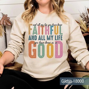 May include: A beige sweatshirt with a colorful graphic print that reads "and all my life you have been FAITHFUL AND ALL MY LIFE you have been so, so GOOD". The text is in a retro style font with a distressed look. The sweatshirt is a Gildan 18000.