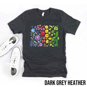 May include: A dark grey heather t-shirt with a colorful floral design. The flowers are arranged in a rainbow pattern, with red, orange, yellow, green, blue, and purple flowers.