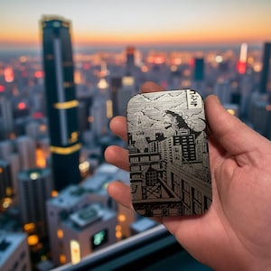 May include: A black and white metal tin with a graphic of a monster attacking a city. The tin has the text "TOKY" on the side.