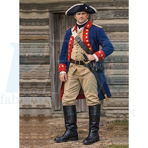 Op de afbeelding: Een historisch kostuum met een blauwe jas met rode bies, gouden knopen en een wit vest. De outfit bevat beige kniebroeken, zwarte laarzen en een steekhoed. Een zwaard is aan de riem bevestigd.