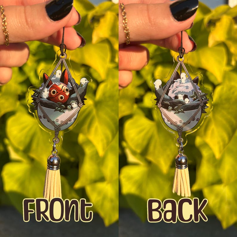 May include: Clear acrylic earrings featuring a cartoon design. The earrings have a triangular shape with a macrame-style basket design. The front earring features a red and white character, while the back earring shows a white and gray character. Each earring has a silver-colored charm and a beige tassel.