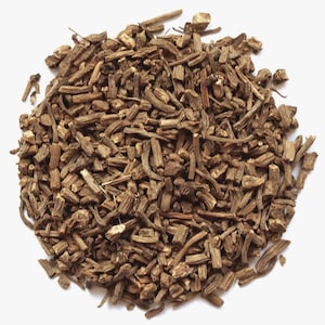 May include: A close-up shot of a pile of dried, chopped valerian root. The pieces are various sizes and shapes, with a light brown color. The root appears to be freshly harvested and ready for use.