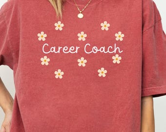 May include: A crimson red t-shirt with a white daisy pattern and the text "Career Coach" printed on the front.