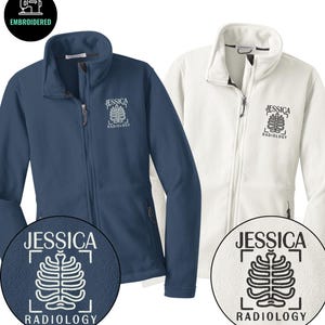 May include: Two fleece jackets, one navy blue and one white, with a full zipper and a high collar. Each jacket has the name "JESSICA" and "RADIOLOGY" embroidered on the chest, along with a stylized rib cage design. The jackets are embroidered.