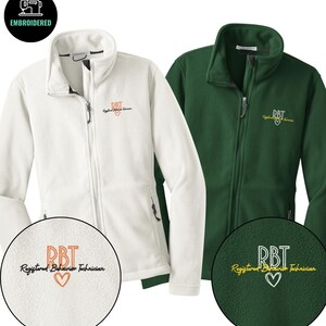 May include: Two fleece jackets, one white and one green, with a full zipper and a high collar. The jackets have the embroidered text "RBT Registered Behavior Technician" with a heart symbol. The top left corner has a black circle with the word "EMBROIDERED".