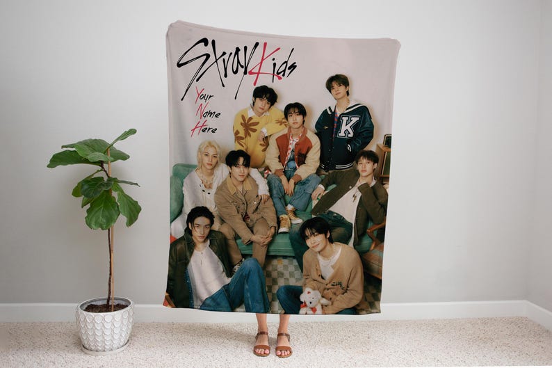 Puede incluir: Una manta de tejido suave con un grupo de ocho j&oacute;venes, con el texto "Stray Kids" y "Your Name Here" impreso en la manta. Los hombres visten ropa informal y est&aacute;n sentados en un sof&aacute;.