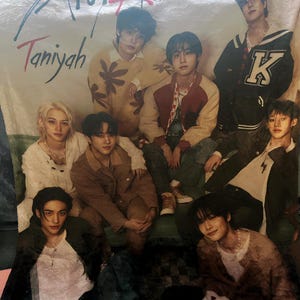 Puede incluir: Una manta blanca con un grupo de siete j&oacute;venes vestidos con ropa informal. La manta tiene el texto "Stray Kids" y "Taniyah" impreso en ella.
